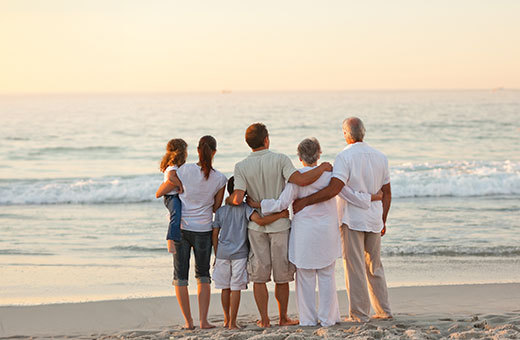 Familia y amigos abrazados caminando en la playa